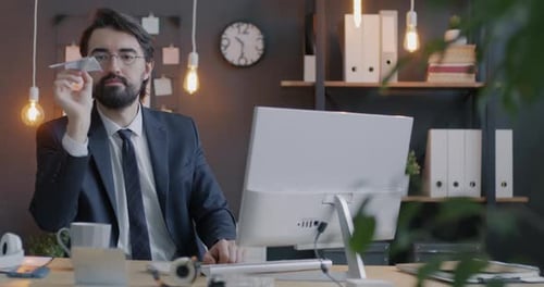 Schleife eines kreativen Geschäftsmannes aus dem Nahen Osten, der Papierflugzeug fliegt und Spaß im modernen Büro hat