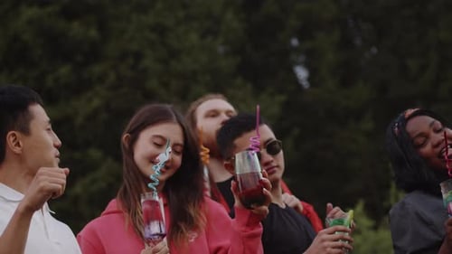 Young Adults Celebrating Outdoors With Colorful Drinks