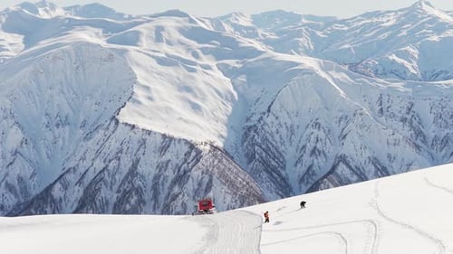 Skiers and Snowcat in Mountainous Winter Landscape