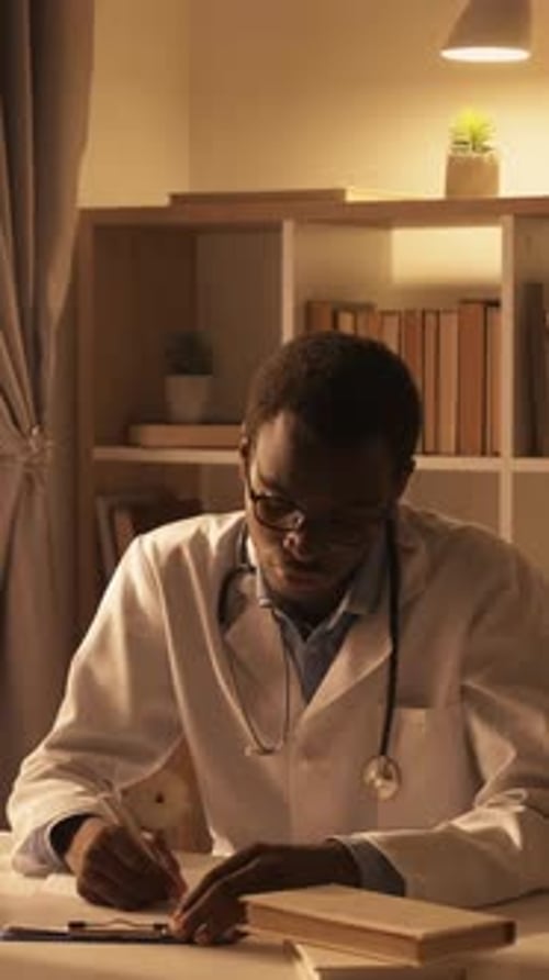 Doctor Working and Writing at Desk at Night