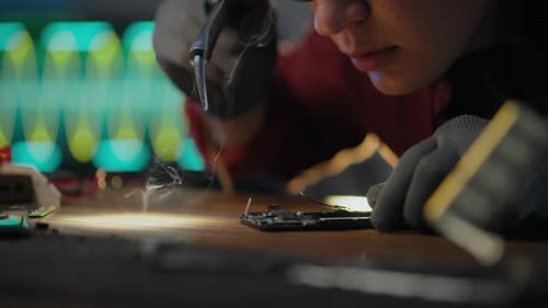Young Adult Repairing Electronics with Soldering Iron