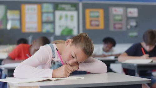In school, girl smiling and sitting at desk with open book in classroom