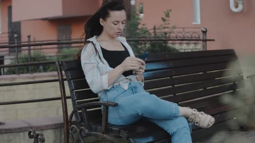 Woman Relaxing on a Bench Using Phone
