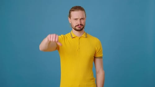 Un jeune homme barbu insatisfait du résultat montre les pouces baissés