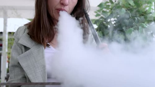 girl woman smoking hookah in terrace restaurant sitting with coffee cup on table,