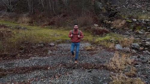 tourist man with jacket and backpack walking in front of the fjord. Back view of a hiker alone by th