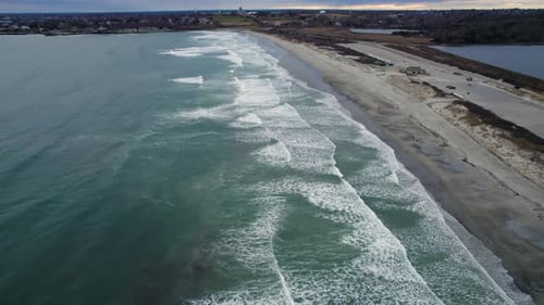 Aerial of ocean waves crashing on a beach on a cloudy day. Drone of sea water on the coast on a stor