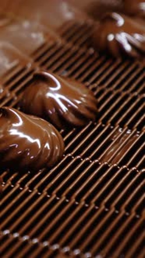 Marshmallows being deepened into a thick layer of chocolate.