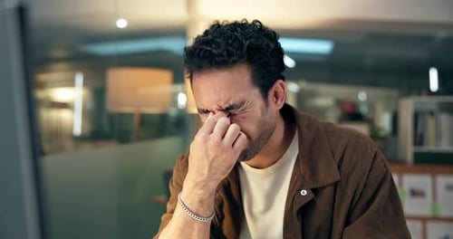 Stressed Man Rubbing Eyes at Computer in Office