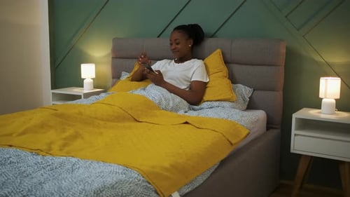 Woman Relaxing in Bed Using Her Mobile Phone