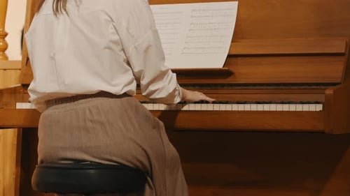 Woman Plays Piano Indoors Reading Sheet Music