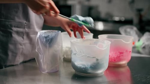 Nahaufnahme: Bäckerin in professioneller Küche füllt Sahnepaste in einen Spritzbeutel