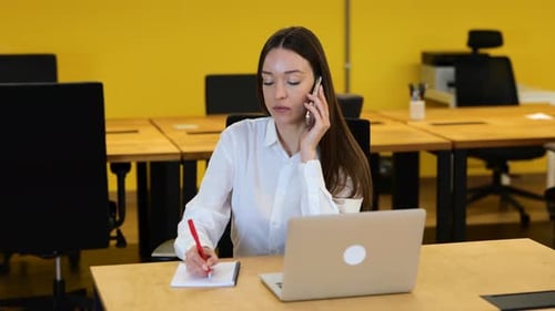 Woman Talking on Phone and Taking Notes in Office