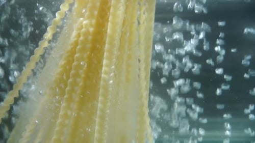 Pasta Falls in Boiling Water. Water Bubbles Boiling. Beautiful Water Background. Close