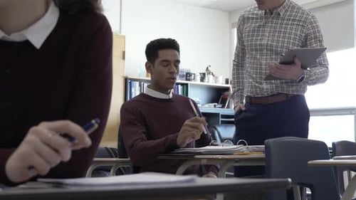 High School Teacher Helping Student with Homework in Classroom Adult