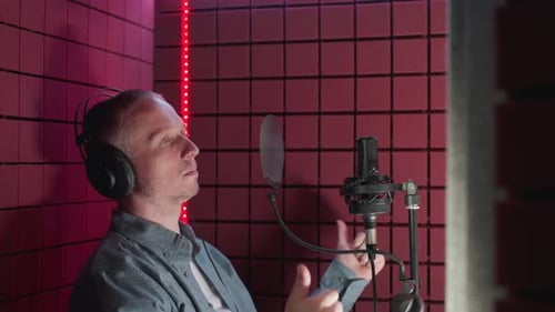Man in Studio with Headphones Singing Into Microphone