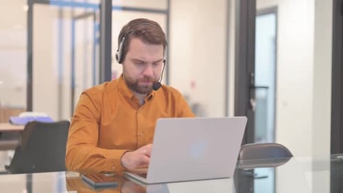 Young Man with Headset Working in Call Center