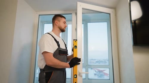 Man Checks Level on Window Frame in Apartment