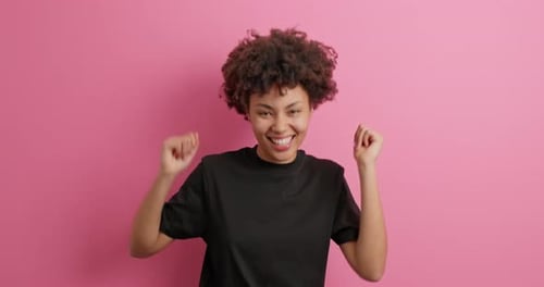 Happy woman dancing against a pink background