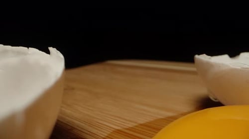 Ein zerbrochenes Hühnerei mit Eigelb darin auf einem Holztisch. Dolly Slider extreme Nahaufnahme
.