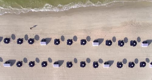 Geometric beach chairs lined up on the white sand of a Florida beach overhead