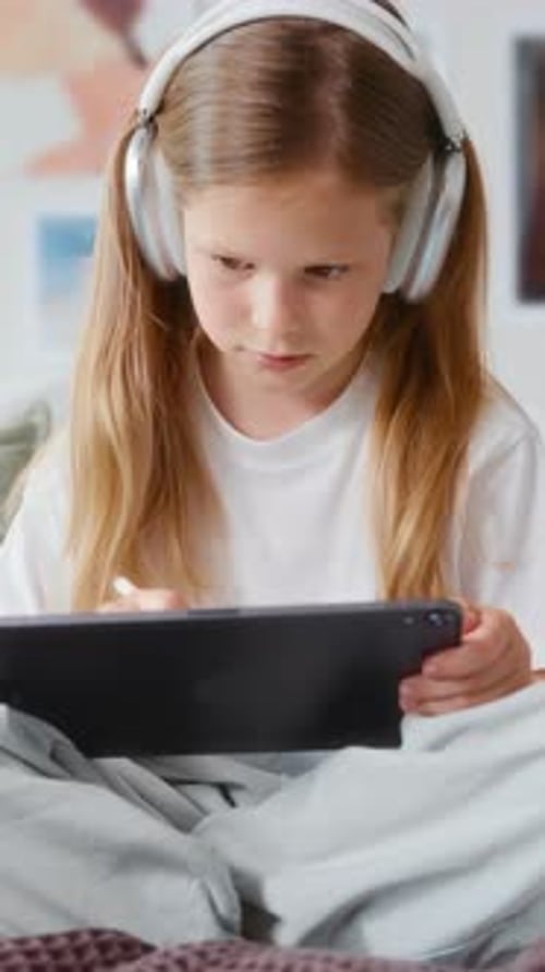 Girl in Headphones Drawing on Tablet and Making Eye Contact with the Camera
