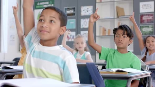 Biracial boys and girls raise their hands in a classroom at school