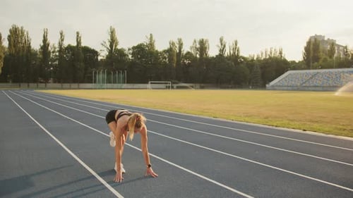 Sporty Blonde Takes Low Start Starts Running on a Running Track in the Stadium