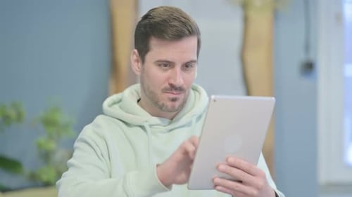 Young Adult Interacting with Tablet and Smiling Indoors