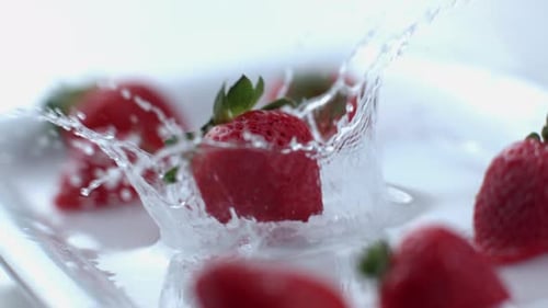 Strawberry Splashing into Water on a White Plate