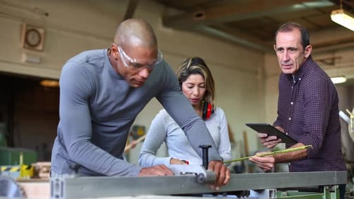 Carpenters Working Together in Workshop Measuring Wood