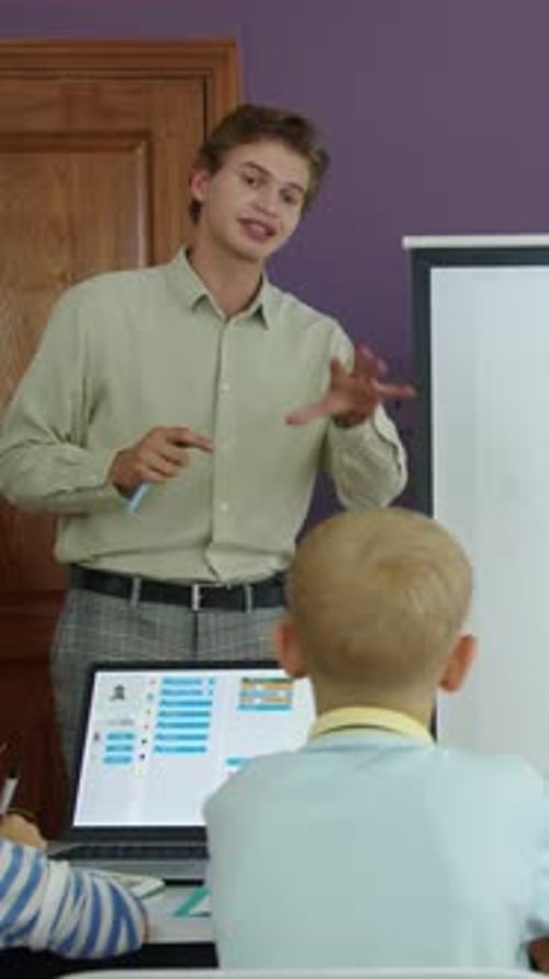 Young Adult Tutoring Two Children With a Laptop