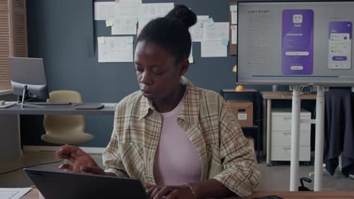 Portrait of Black female UI Designer with Cup Using Laptop at Office