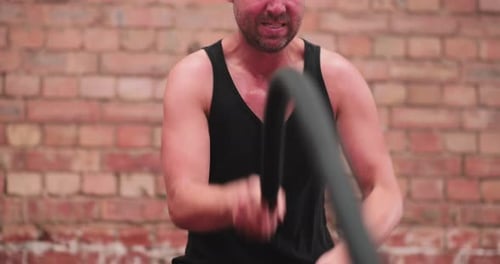 Determined Man Doing Battle Rope Workout at Gym