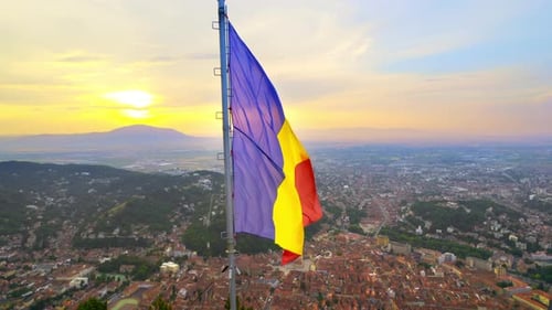 Romanian Flag Waving above City at Sunrise