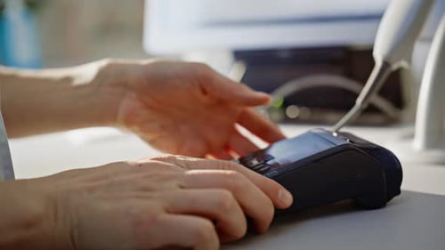 Verkäufer gibt Zahlungsdetails per Hand ein und gibt den Terminalautomaten dem Kunden in Nahaufnahme