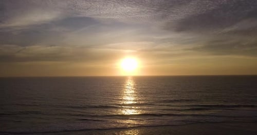 Luftaufnahme der Meereslandschaft bei Sonnenuntergang, Flug über die Meereswasseroberfläche in Richtung Sonne bei Sonnenuntergang, Goldene Wolke