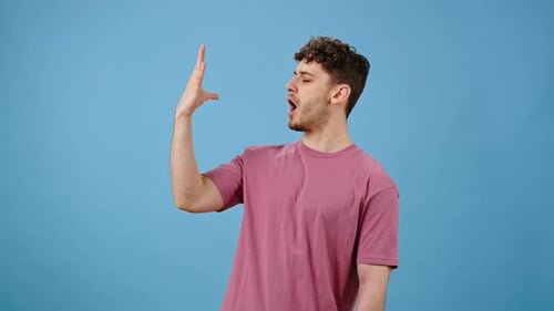 Junger Mann mit leckerer Geste küsst die Finger und sagt Bellissimo isoliert auf blauem Hintergrund