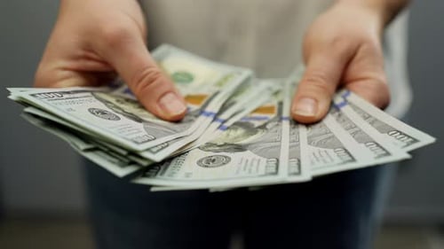 Person Handing Over Stack of Hundred Dollar Bills