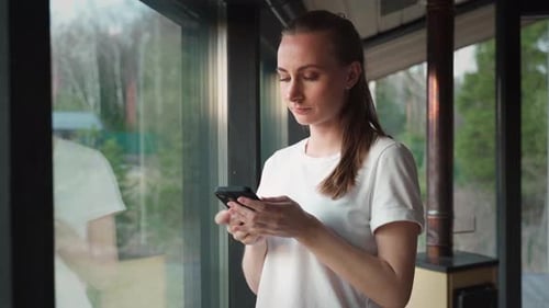 Woman Talking on Phone by Window Inside Home