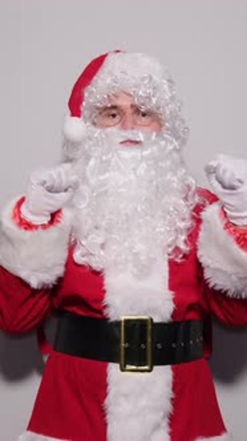 Man Dressed as Santa Claus Dancing Against Gray Backdrop