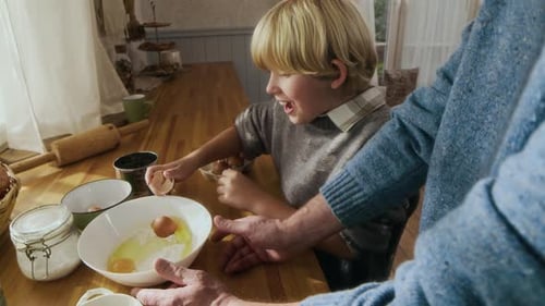 Child Cracks Eggs Into Bowl While Baking