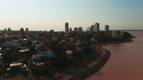 A lateral aerial view showcasing the skyline of Posadas against the backdrop of the Paraná River.