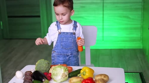 Little Boy Plays With Fresh Vegetables in Kitchen