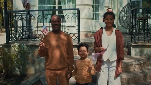Family Holds American Flags in Front of Home
