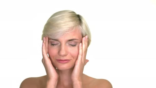 Studio portrait of a beautiful and attractive blond woman gently touching her face. Expressive clip
