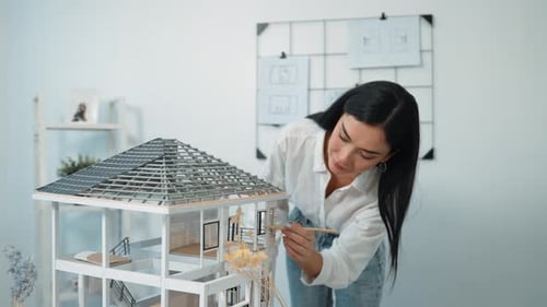 Young beautiful smart engineer measure house model by using pencil. Immaculate.