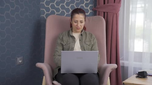 Woman Works on Laptop in Armchair at Home