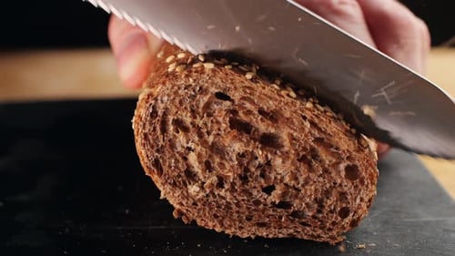 Cutting seeded bread with knife in close up