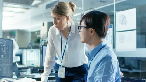 Two Colleagues Collaborate Over Computer Work in Office